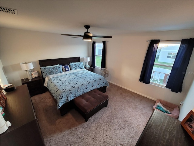 carpeted bedroom with visible vents, baseboards, and a ceiling fan