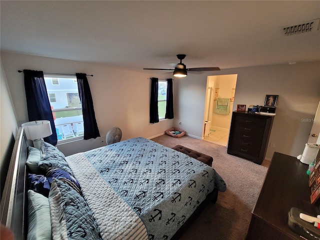 bedroom featuring visible vents, a ceiling fan, ensuite bath, carpet floors, and baseboards