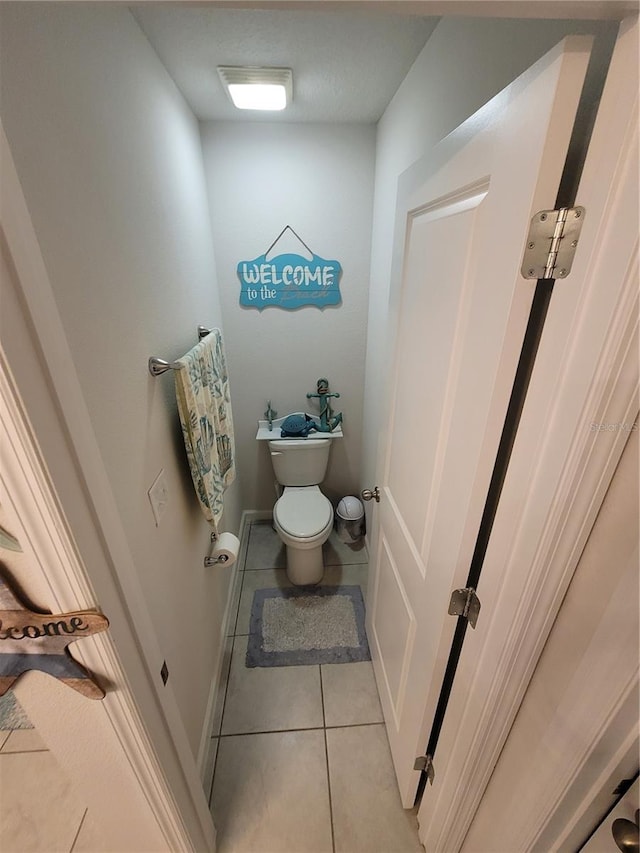 bathroom featuring tile patterned floors, toilet, and baseboards