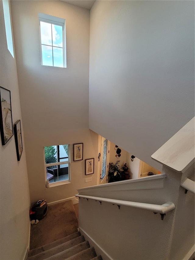 staircase with a high ceiling and baseboards