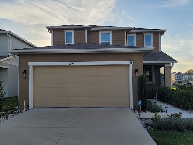 traditional-style house featuring stucco siding and concrete driveway