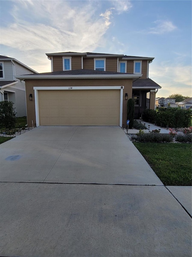 traditional home with stucco siding, concrete driveway, and a garage