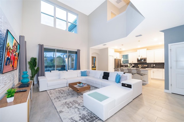 tiled living room featuring sink and a high ceiling