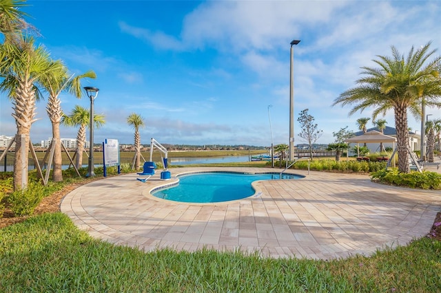 view of swimming pool featuring a patio and a water view