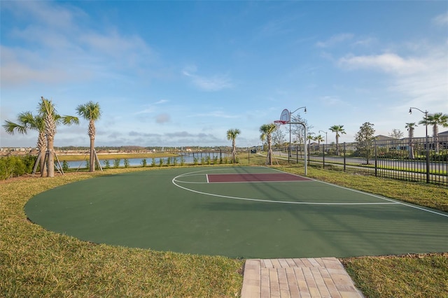 view of basketball court featuring a water view and a yard