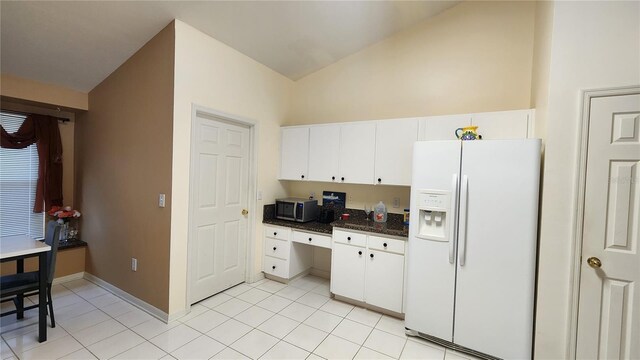 kitchen with white cabinetry, vaulted ceiling, light tile patterned floors, and white fridge with ice dispenser