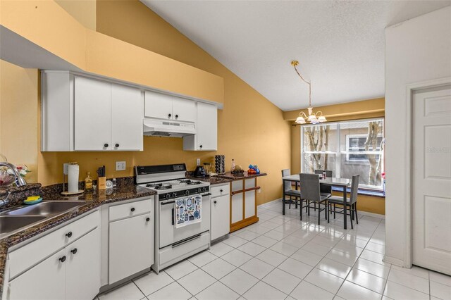 kitchen featuring vaulted ceiling, an inviting chandelier, white range with gas cooktop, pendant lighting, and white cabinets