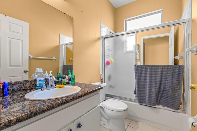 full bathroom with combined bath / shower with glass door, vanity, toilet, and tile patterned floors