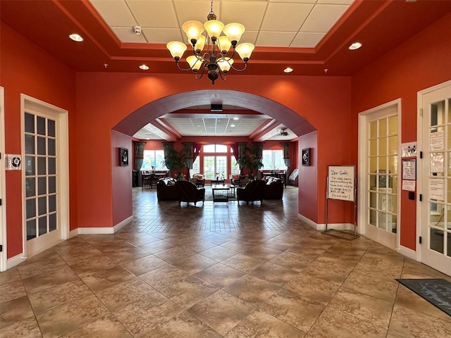 interior space with a chandelier, a tray ceiling, tile floors, and a high ceiling