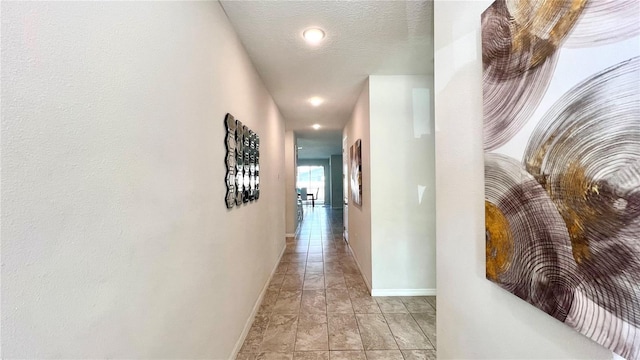 corridor with light tile floors and a textured ceiling