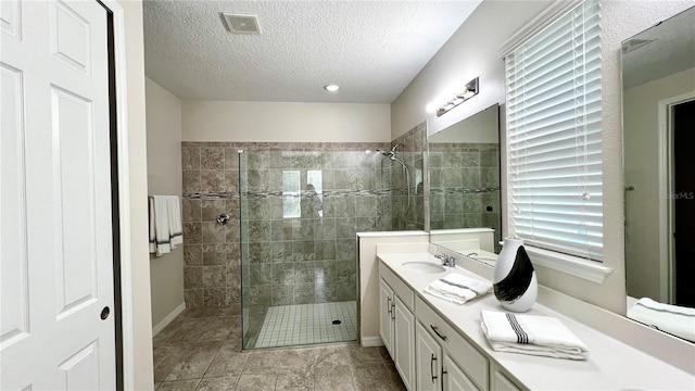 bathroom with a shower with shower door, a textured ceiling, vanity, and tile flooring