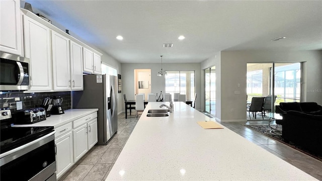 kitchen with hanging light fixtures, plenty of natural light, white cabinetry, and stainless steel appliances