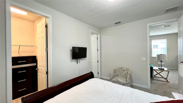 bedroom with light colored carpet and a textured ceiling