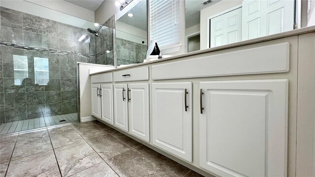 bathroom featuring tiled shower, vanity, and tile floors