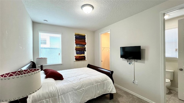 tiled bedroom featuring connected bathroom and a textured ceiling