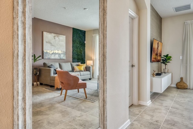 hall with light tile floors and a textured ceiling