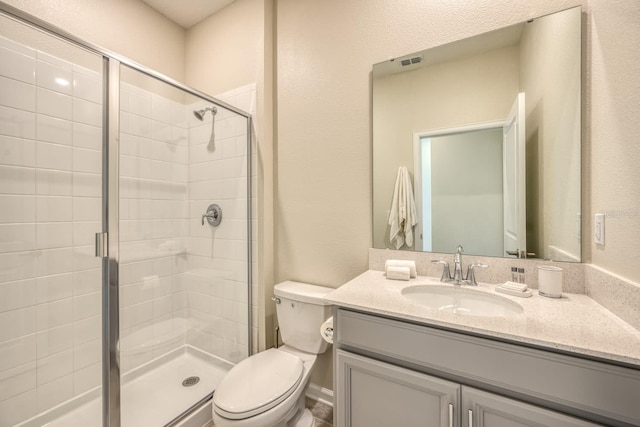 bathroom featuring vanity, a shower with shower door, and toilet