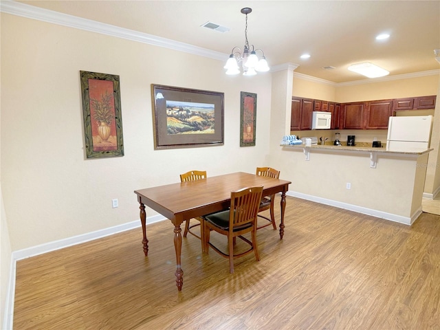 dining space featuring crown molding, a notable chandelier, and light wood-type flooring