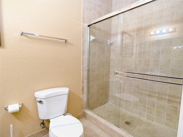 bathroom with a shower with shower door and toilet