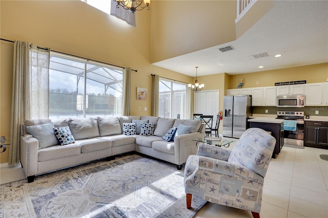 living room featuring light tile patterned flooring, a towering ceiling, a chandelier, and a textured ceiling