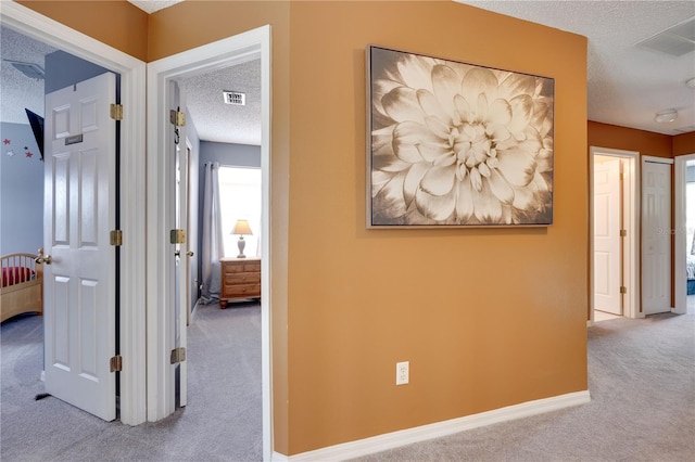 hallway featuring light carpet and a textured ceiling