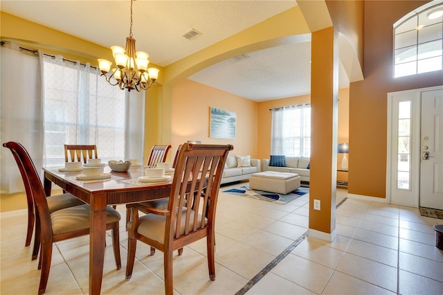 dining space with light tile patterned floors, a textured ceiling, and a chandelier