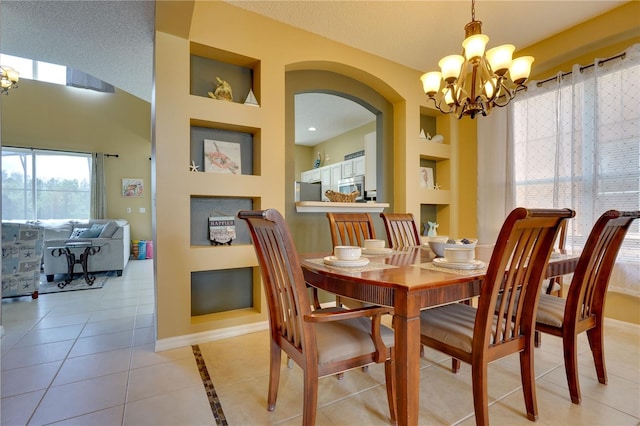 tiled dining room featuring a textured ceiling, a chandelier, and built in shelves