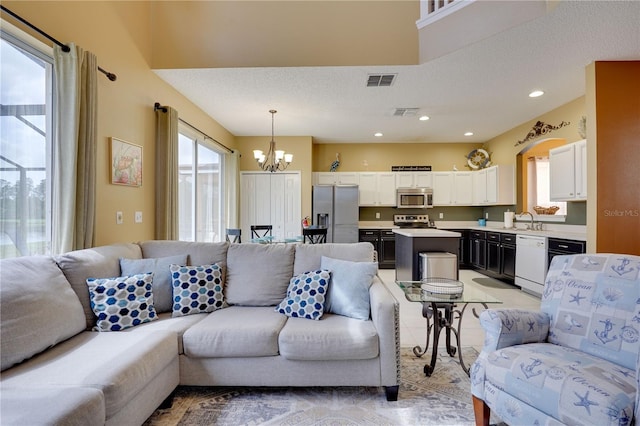 living room with an inviting chandelier, sink, light tile patterned floors, and a textured ceiling