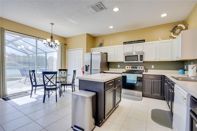 kitchen with white cabinetry, stainless steel appliances, decorative light fixtures, and sink