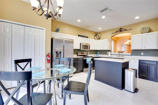 kitchen featuring pendant lighting, light tile patterned floors, appliances with stainless steel finishes, an inviting chandelier, and a kitchen island