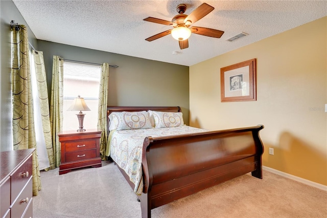 bedroom with ceiling fan, light colored carpet, and a textured ceiling