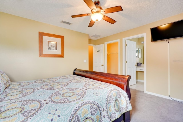 bedroom with a spacious closet, light colored carpet, ceiling fan, a textured ceiling, and a closet