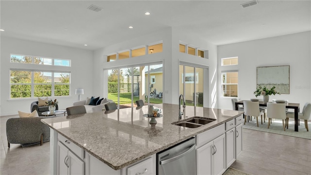 kitchen featuring dishwasher, a center island with sink, sink, white cabinetry, and light hardwood / wood-style floors