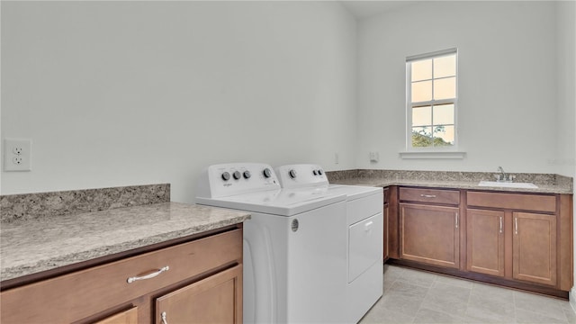 clothes washing area with light tile patterned floors, cabinets, sink, and washing machine and clothes dryer