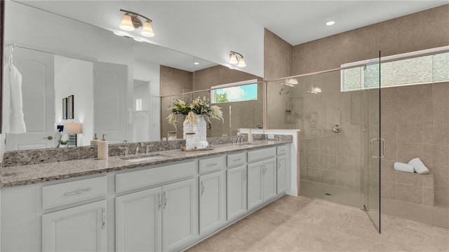 bathroom with a shower with door, a healthy amount of sunlight, and vanity