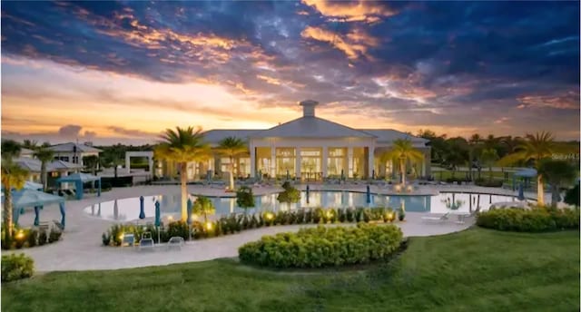 pool at dusk featuring a gazebo, a patio area, and a yard