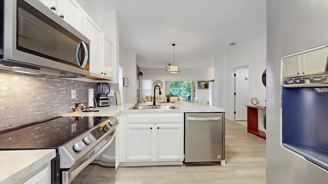 kitchen featuring light hardwood / wood-style floors, tasteful backsplash, white cabinetry, stainless steel appliances, and pendant lighting