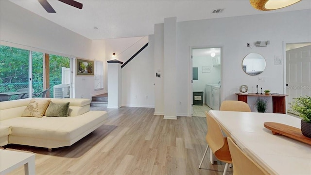 living room featuring ceiling fan, washing machine and dryer, and light wood-type flooring