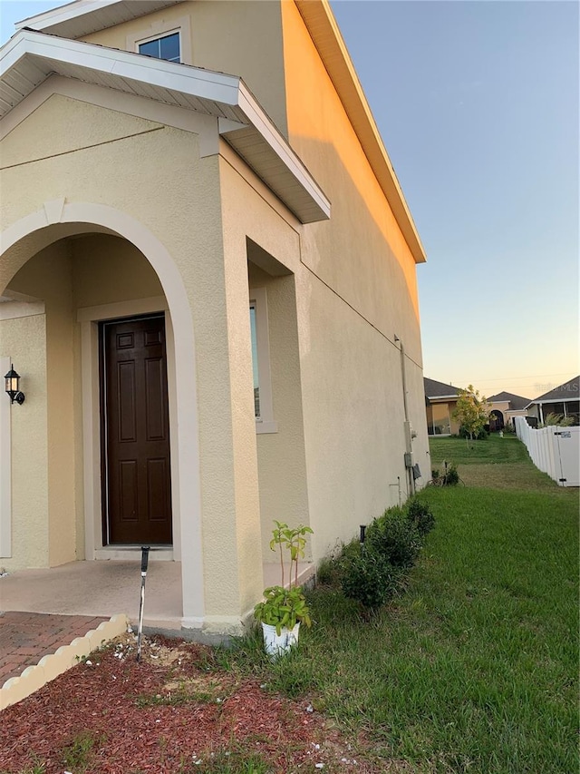 exterior entry at dusk featuring a yard