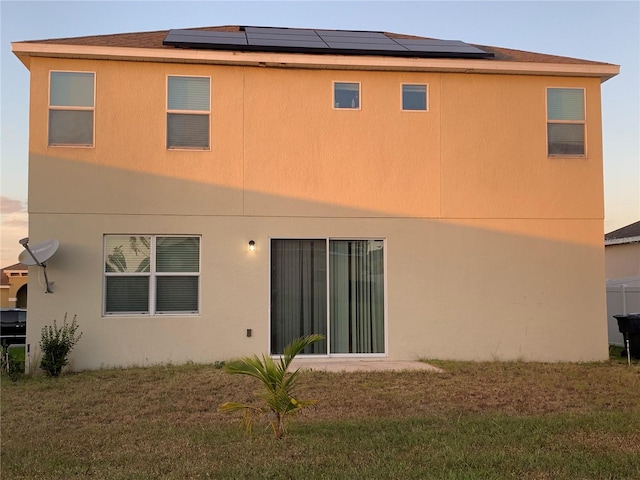 back of house featuring a lawn and solar panels