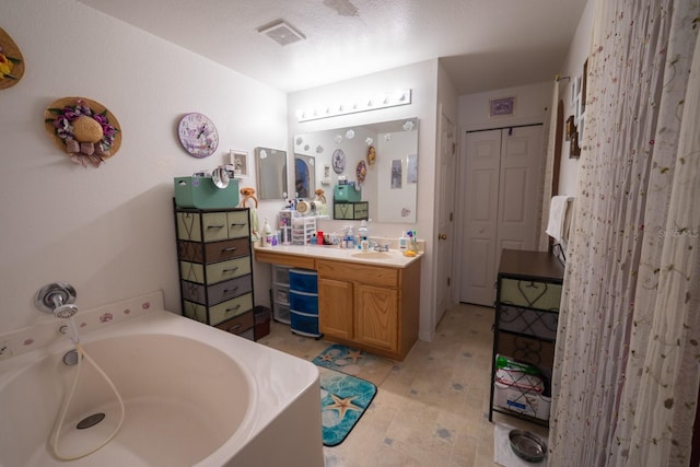 bathroom with vanity with extensive cabinet space, tile flooring, a bath, and a textured ceiling