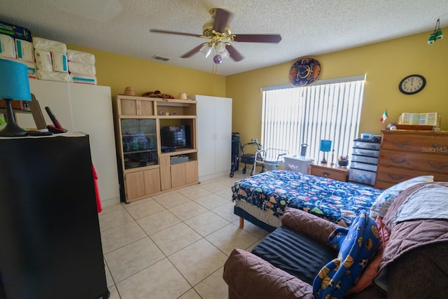 bedroom featuring a textured ceiling, ceiling fan, and light tile floors