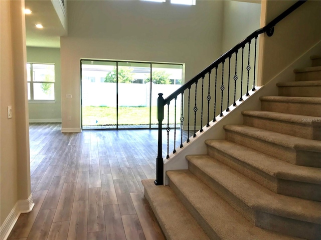 stairs featuring hardwood / wood-style floors and a high ceiling