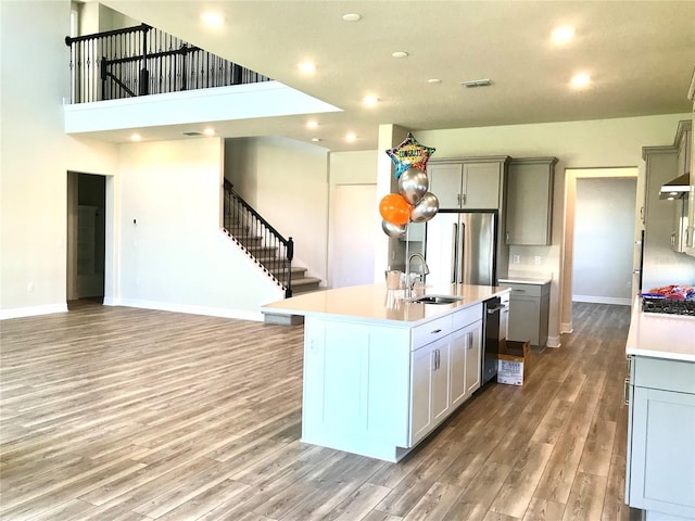 kitchen featuring a kitchen island with sink, appliances with stainless steel finishes, sink, light hardwood / wood-style flooring, and gray cabinets