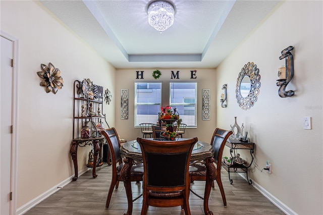 dining area featuring a chandelier, a tray ceiling, and dark wood-type flooring