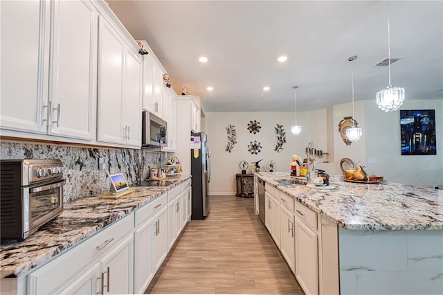 kitchen featuring stainless steel appliances, tasteful backsplash, light hardwood / wood-style flooring, white cabinetry, and hanging light fixtures