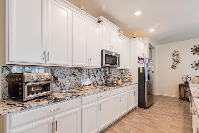 kitchen with stainless steel appliances, white cabinets, and light stone countertops