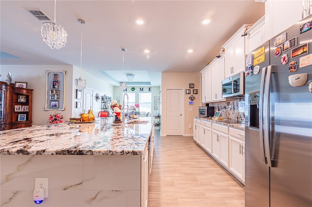 kitchen featuring white cabinets, hanging light fixtures, and stainless steel appliances