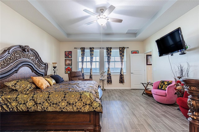 bedroom featuring a tray ceiling, ceiling fan, and light hardwood / wood-style flooring