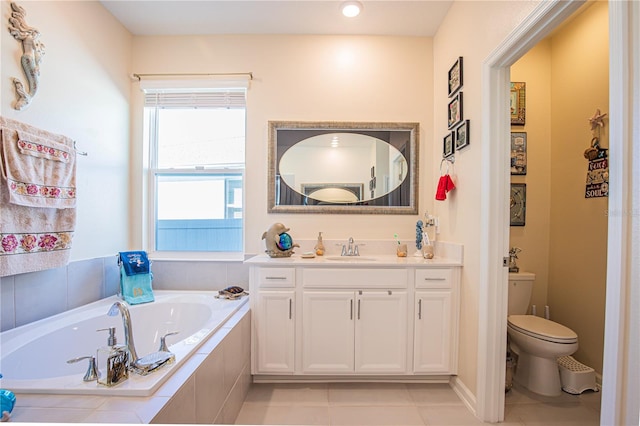 bathroom with toilet, vanity, tiled tub, and tile flooring